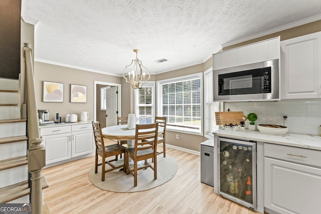 kitchen featuring built in microwave, light stone countertops, wine cooler, and light hardwood / wood-style flooring