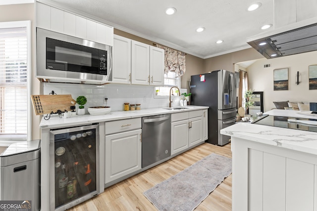 kitchen with appliances with stainless steel finishes, light stone countertops, wine cooler, and sink