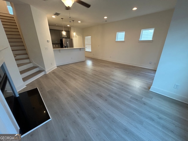 unfurnished living room featuring ceiling fan and hardwood / wood-style flooring