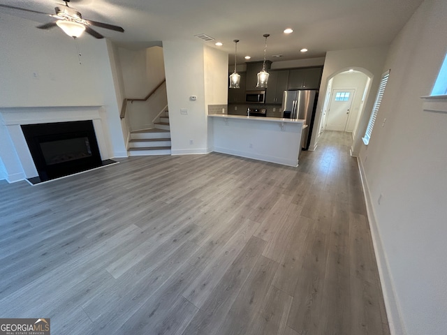 unfurnished living room featuring ceiling fan and wood-type flooring