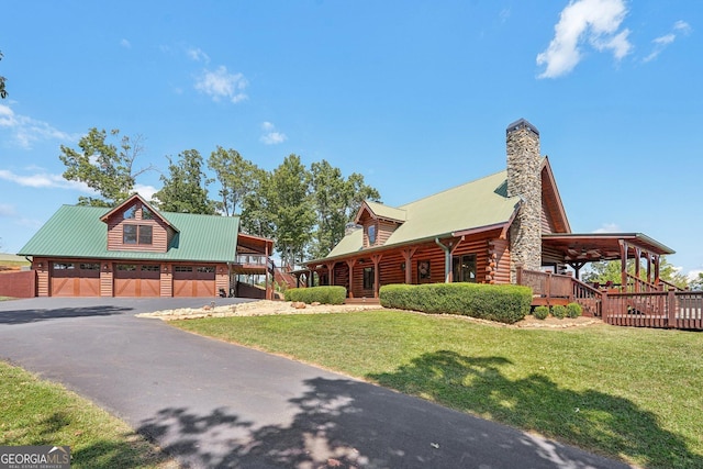 log home featuring a chimney, metal roof, log siding, a garage, and a front lawn