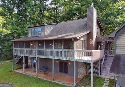 back of property with a sunroom, a wooden deck, and a patio area