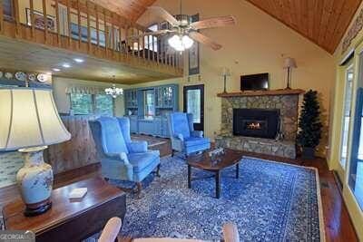 living room featuring high vaulted ceiling, ceiling fan with notable chandelier, a fireplace, and a healthy amount of sunlight