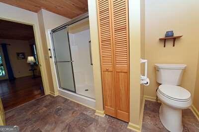 bathroom with wood ceiling, toilet, hardwood / wood-style flooring, and an enclosed shower