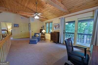 carpeted home office featuring ceiling fan, wooden ceiling, and vaulted ceiling with beams