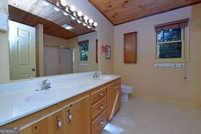 bathroom featuring wooden ceiling, vanity, toilet, and walk in shower