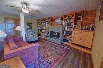 living room with hardwood / wood-style floors, ceiling fan, and a stone fireplace