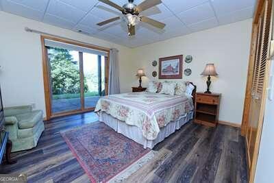 bedroom featuring dark wood-type flooring, ceiling fan, a paneled ceiling, and access to outside