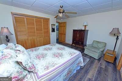 bedroom featuring dark wood-type flooring, a closet, ceiling fan, and a paneled ceiling