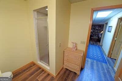 bathroom with toilet, wood-type flooring, and an enclosed shower