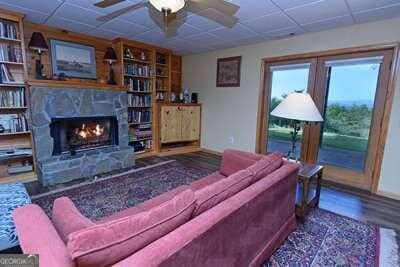 living room featuring a drop ceiling, ceiling fan, dark hardwood / wood-style floors, and a fireplace