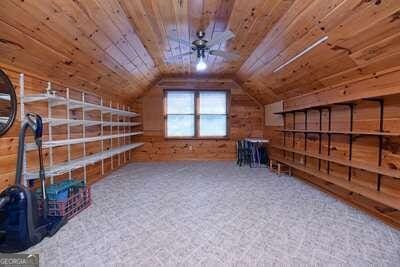 additional living space with vaulted ceiling, ceiling fan, wooden walls, and wood ceiling