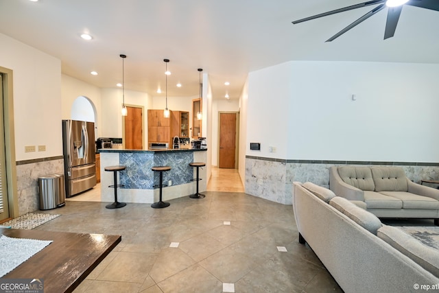 tiled living room with ceiling fan and sink