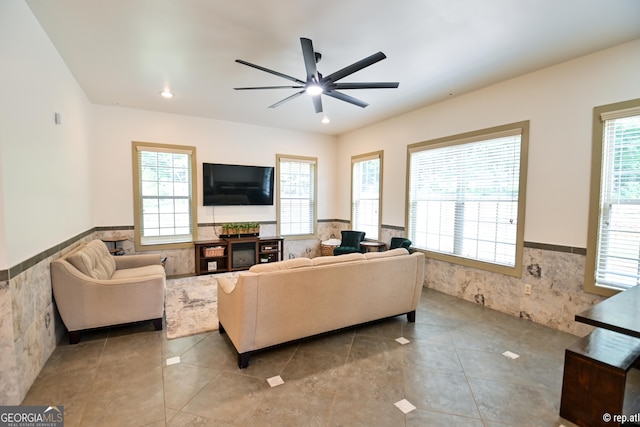 living room featuring plenty of natural light, ceiling fan, and tile walls