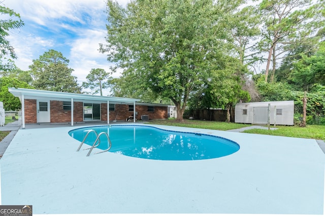 view of pool with a patio area, a lawn, and a shed