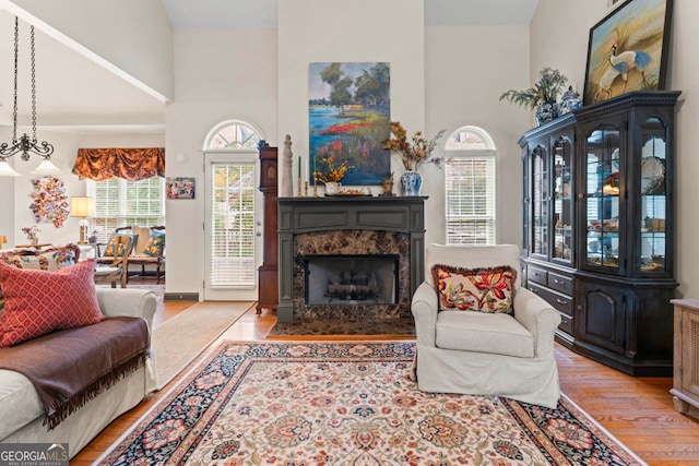 living room featuring a high ceiling, hardwood / wood-style floors, a premium fireplace, and plenty of natural light