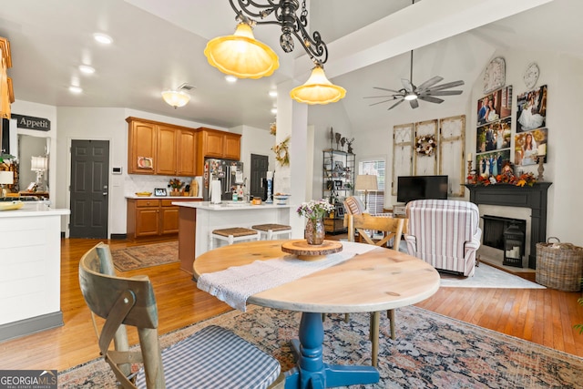 dining area featuring vaulted ceiling, ceiling fan, and light hardwood / wood-style flooring