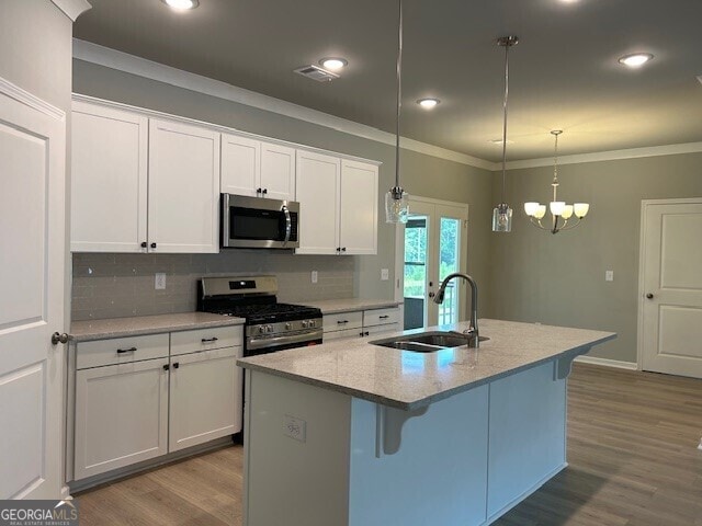 kitchen featuring sink, hanging light fixtures, an island with sink, stainless steel appliances, and white cabinets