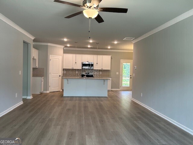 kitchen with tasteful backsplash, an island with sink, appliances with stainless steel finishes, and white cabinets