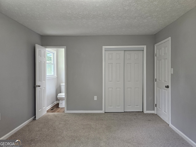 unfurnished bedroom with a closet, light carpet, and a textured ceiling