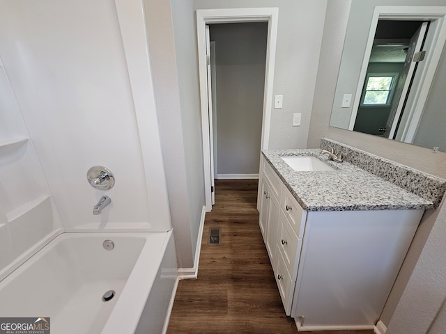 bathroom featuring vanity, washtub / shower combination, and wood-type flooring