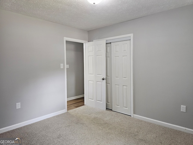 unfurnished bedroom with a textured ceiling, a closet, and carpet flooring