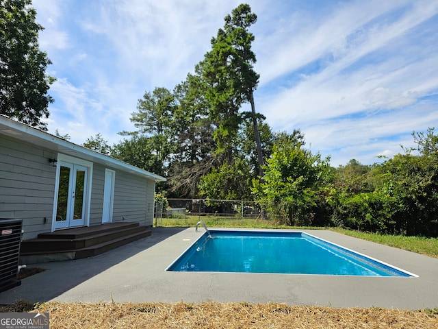 view of swimming pool with a patio area, french doors, and central AC