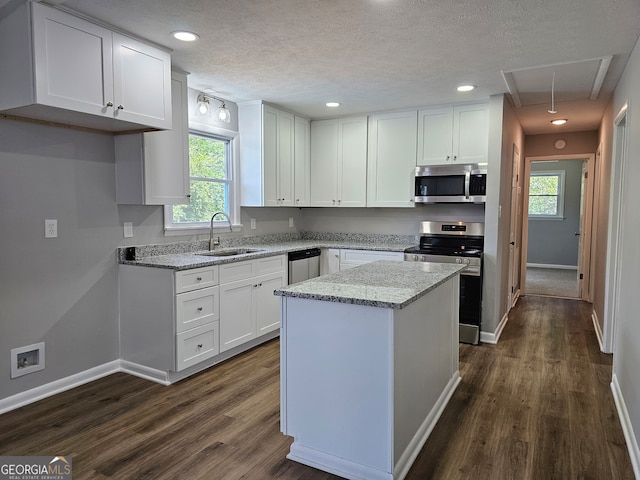 kitchen with white cabinetry, stainless steel appliances, sink, plenty of natural light, and a center island