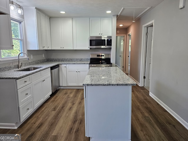 kitchen with dark hardwood / wood-style floors, stainless steel appliances, sink, white cabinets, and a textured ceiling