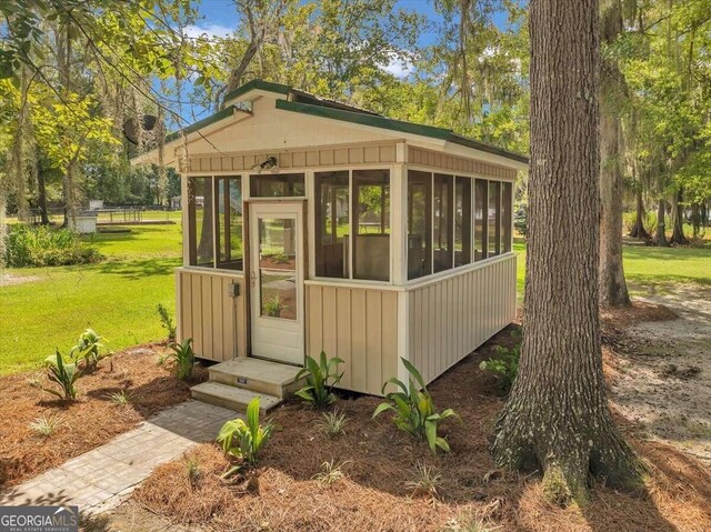 view of outdoor structure with a yard and a sunroom