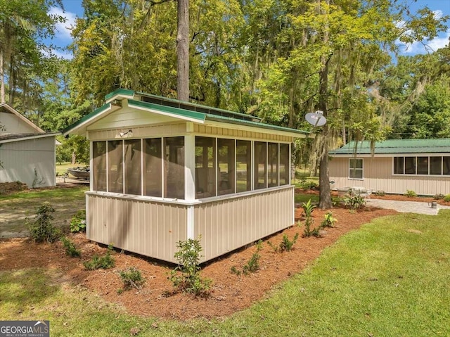 view of outbuilding featuring a sunroom and a lawn