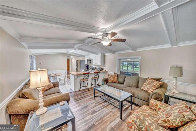 living room with crown molding, lofted ceiling with beams, ceiling fan, and light hardwood / wood-style floors