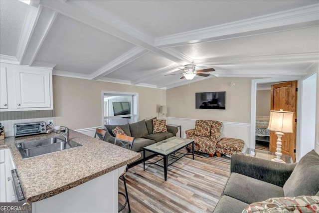 living room featuring crown molding, light hardwood / wood-style flooring, sink, ceiling fan, and lofted ceiling with beams