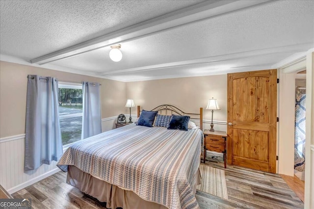 bedroom featuring a textured ceiling, hardwood / wood-style floors, and beam ceiling