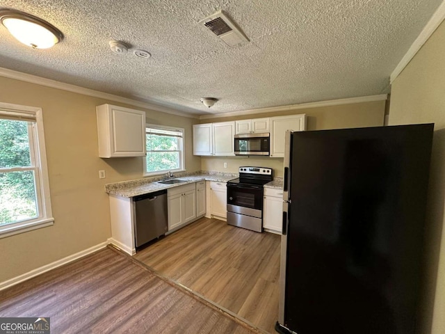 kitchen featuring appliances with stainless steel finishes, light hardwood / wood-style floors, white cabinetry, sink, and a textured ceiling