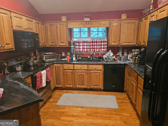 kitchen with lofted ceiling, black appliances, sink, and light hardwood / wood-style flooring