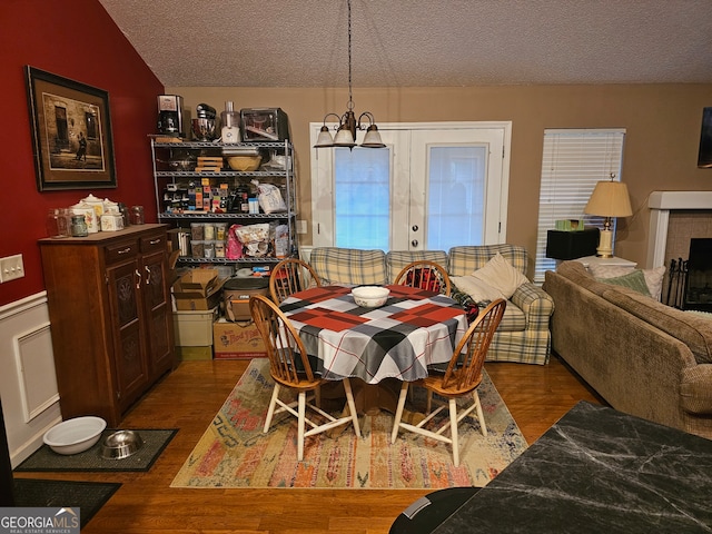 dining area featuring a fireplace, a textured ceiling, dark hardwood / wood-style flooring, and lofted ceiling