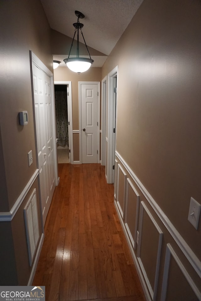 hall with lofted ceiling and hardwood / wood-style floors