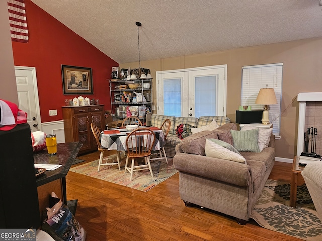 living room with lofted ceiling, hardwood / wood-style floors, and a textured ceiling