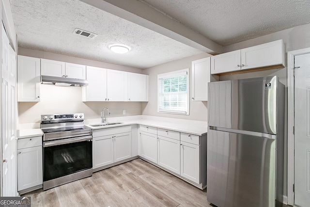 kitchen with light wood finished floors, visible vents, under cabinet range hood, appliances with stainless steel finishes, and a sink