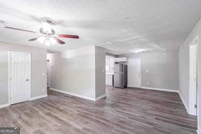 unfurnished living room with dark wood-style floors, a textured ceiling, baseboards, and a ceiling fan