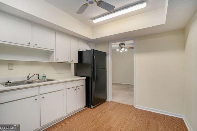 kitchen featuring ceiling fan, light hardwood / wood-style flooring, sink, white cabinets, and black refrigerator