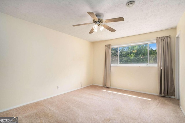 carpeted empty room featuring ceiling fan and a textured ceiling