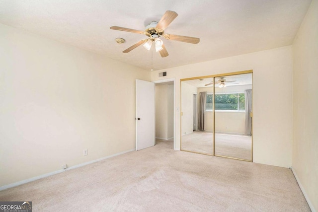 unfurnished bedroom featuring ceiling fan, a closet, and light colored carpet