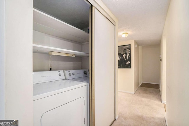 laundry room featuring light carpet, separate washer and dryer, and a textured ceiling