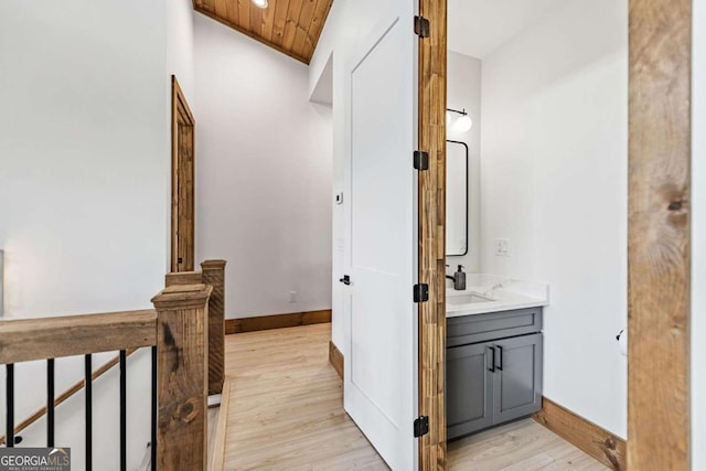 corridor featuring light wood-type flooring, sink, and wooden ceiling