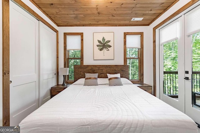 bedroom with multiple windows, wood ceiling, a closet, and access to exterior