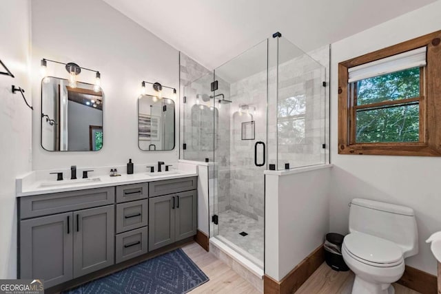 bathroom with hardwood / wood-style floors, toilet, a shower with door, and vanity