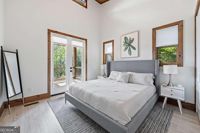 bedroom featuring french doors, light hardwood / wood-style floors, multiple windows, and access to outside