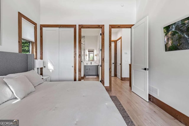 bedroom featuring ensuite bath and light hardwood / wood-style flooring